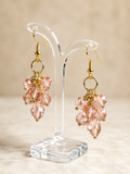 Pink crystal earrings on a clear stand with a beige background